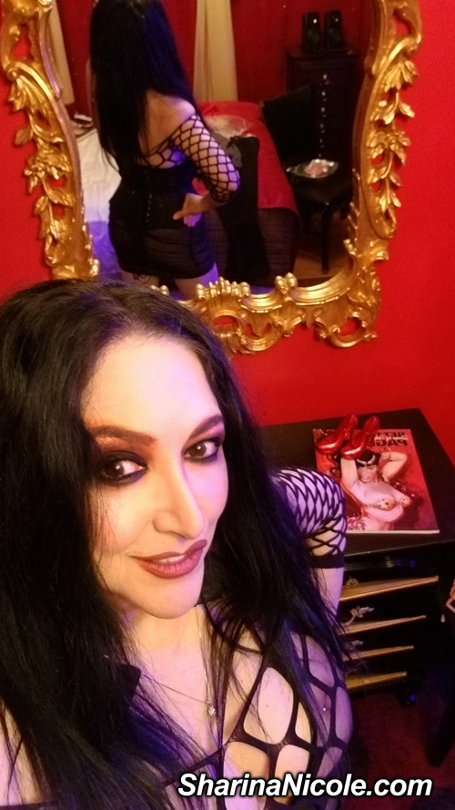 Minneapolis Femdom Dominatrix standing in a red room. Mistress Sharina Nicole femdom domina from Minneapolis, MN in her bdsm domme studio.